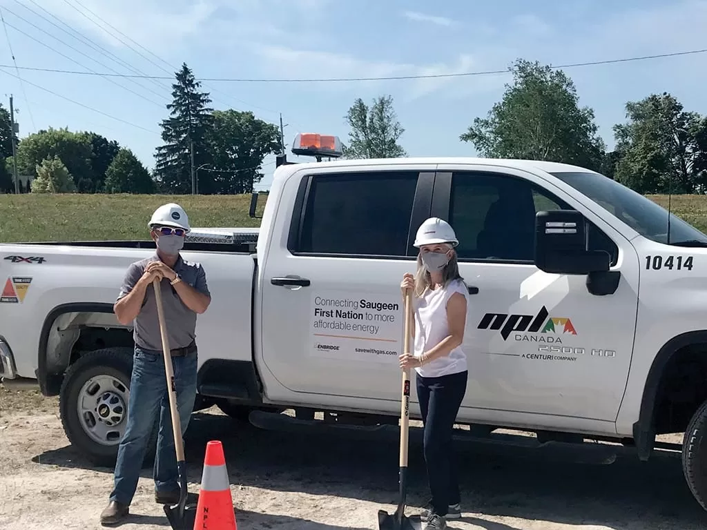 Two workers holding shovels next to NPL Canada truck