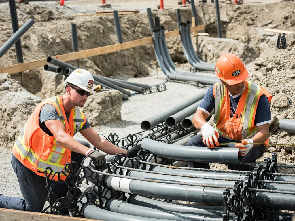 Construction workers handling tube pipes